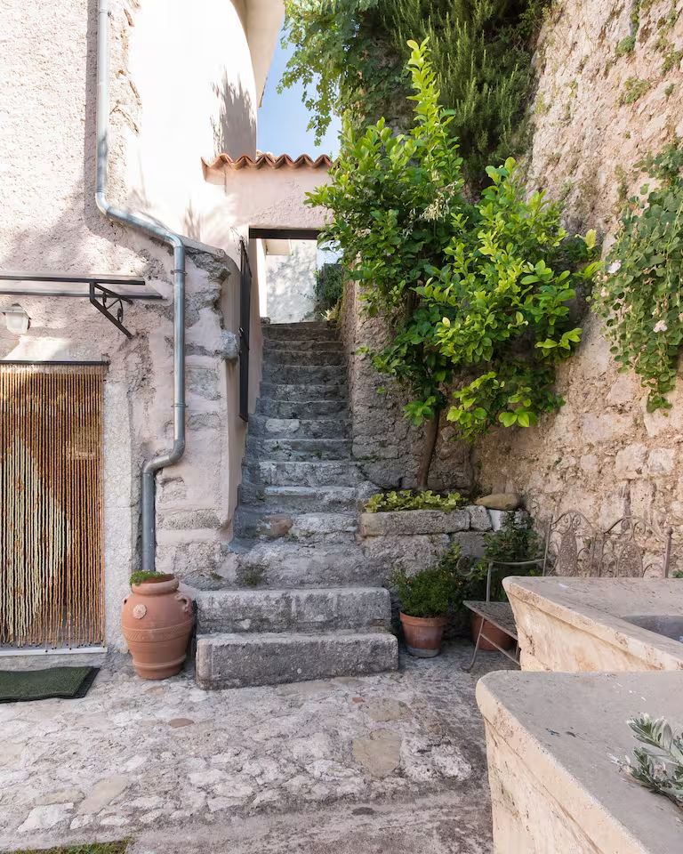 Scalinata in pietra all'ingresso della dimora, tra vasi e piante